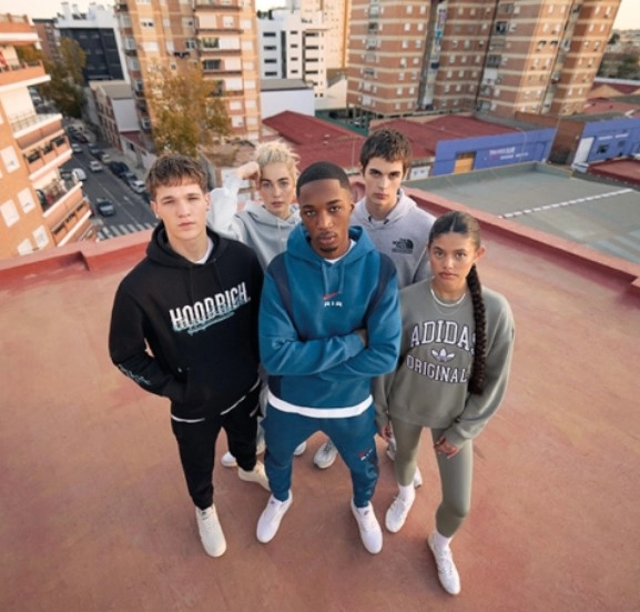 Pet mladih oseb v športnih oblačilih stoji na strehi hiše v blokovskem naselju.